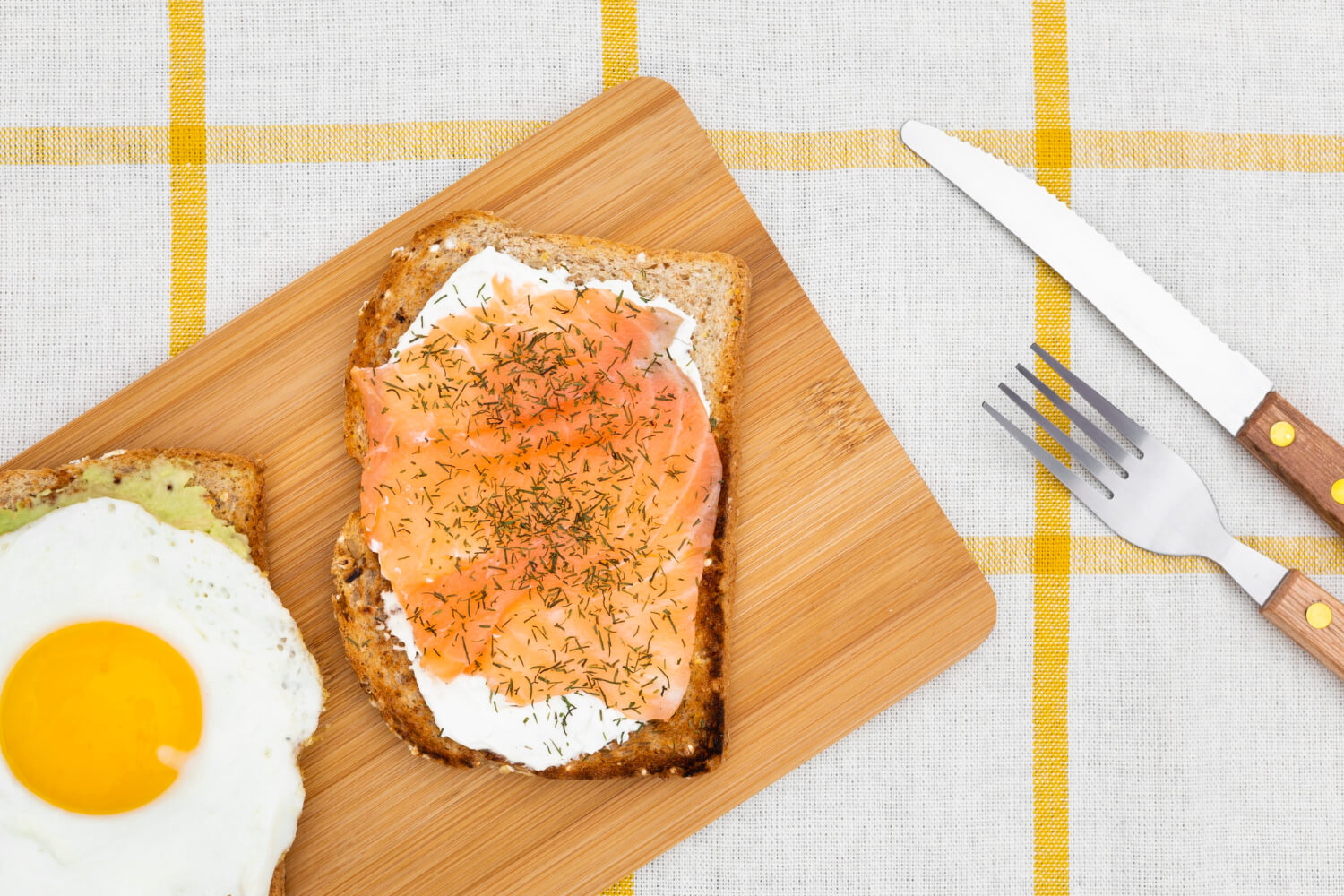 Toast topped with a perfectly cooked egg and sliced avocado, arranged attractively on a white plate.  