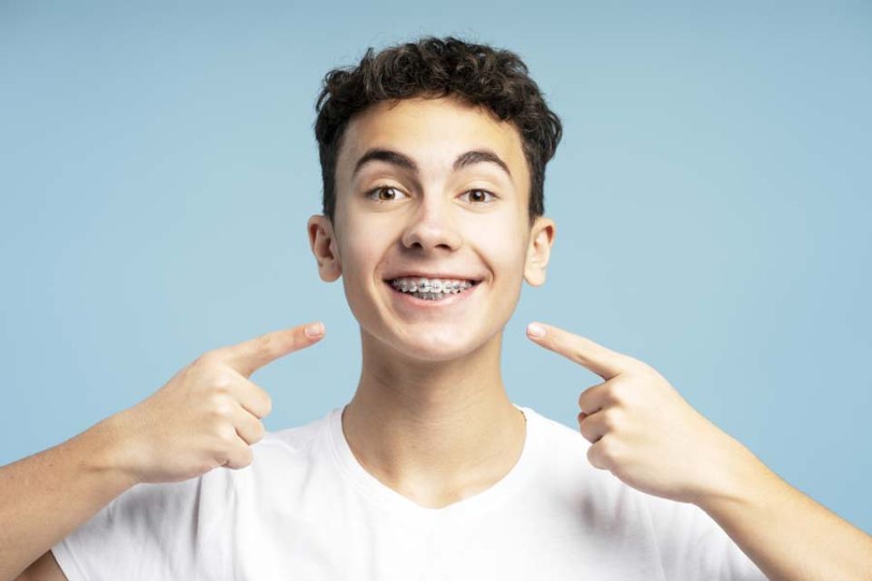 A young man points his fingers directly at the camera, smiling confidently