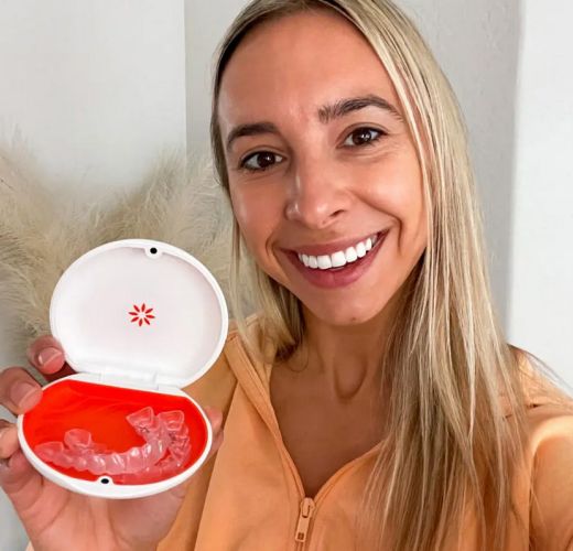 A blonde woman showing her vivera retainers